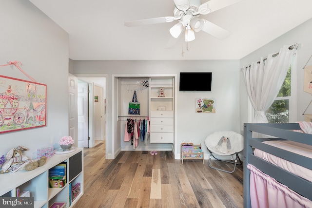 bedroom with a closet, wood finished floors, baseboards, and ceiling fan