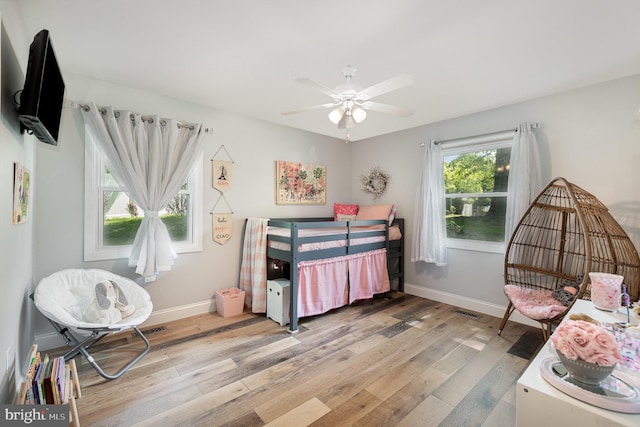 bedroom featuring baseboards, visible vents, a ceiling fan, and wood finished floors