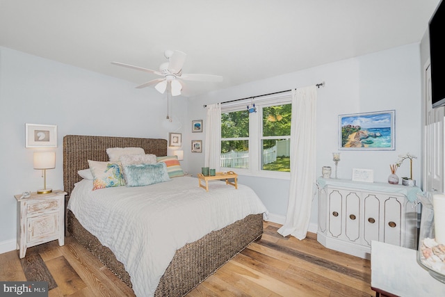 bedroom featuring light wood finished floors, baseboards, and ceiling fan