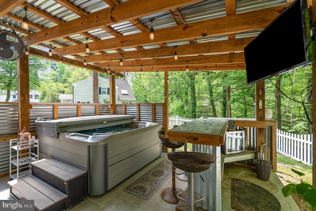 view of patio with a hot tub and fence