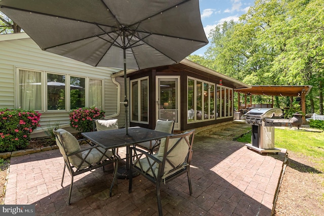 view of patio with a sunroom, outdoor dining area, and grilling area