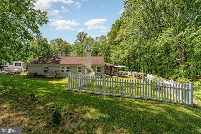 rear view of house featuring a yard, fence, and a chimney