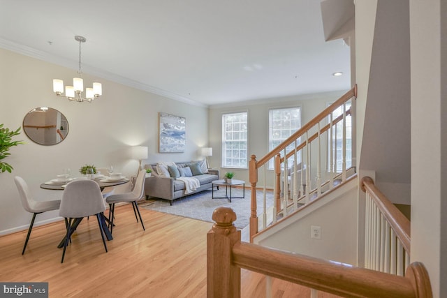 living area with a chandelier, light wood-style flooring, ornamental molding, baseboards, and stairway
