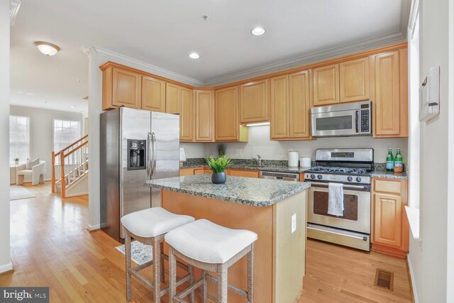 kitchen with appliances with stainless steel finishes, a center island, light wood-style floors, recessed lighting, and light stone countertops