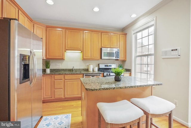 kitchen with stainless steel appliances, a sink, crown molding, light wood-style floors, and light stone counters