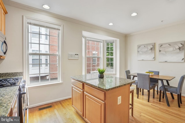 kitchen with stainless steel appliances, ornamental molding, light wood-type flooring, baseboards, and a center island