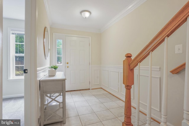 foyer with healthy amount of natural light, stairway, ornamental molding, and light tile patterned flooring