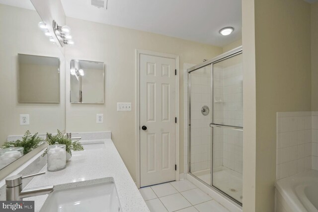 bathroom with tile patterned flooring, a stall shower, a garden tub, and double vanity