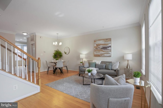 living room with stairs, ornamental molding, a chandelier, wood finished floors, and baseboards