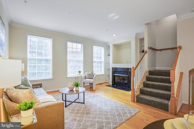 living room with wood finished floors, a fireplace, crown molding, stairs, and baseboards