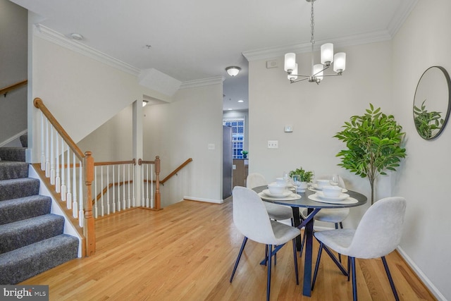 dining area featuring light wood finished floors, crown molding, a chandelier, and baseboards