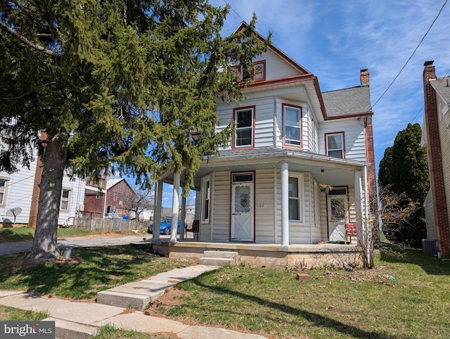 victorian house with a porch, central AC, and a front yard