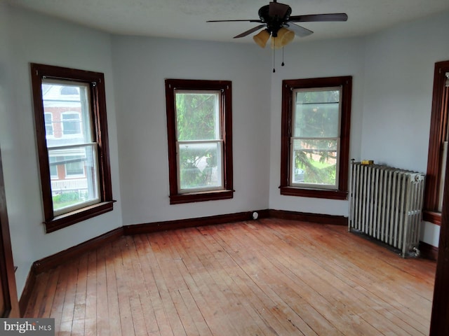 spare room with radiator, light wood finished floors, healthy amount of natural light, and baseboards