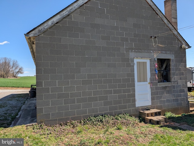 view of home's exterior featuring concrete block siding and a chimney