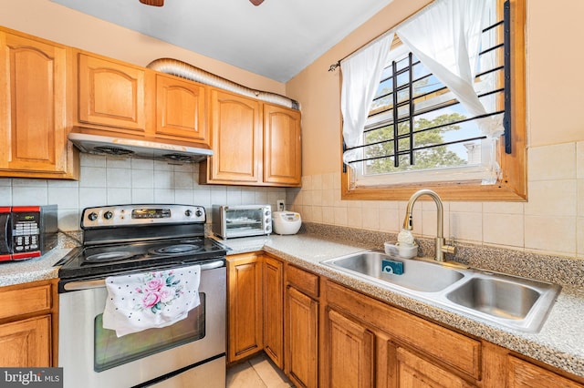 kitchen featuring stainless steel electric range, a sink, under cabinet range hood, and light countertops