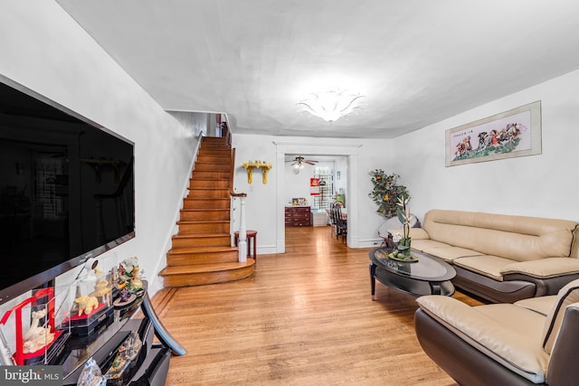 living room featuring stairway, light wood-style flooring, and baseboards