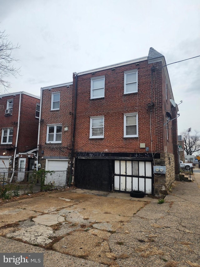 back of house featuring brick siding, a garage, and fence