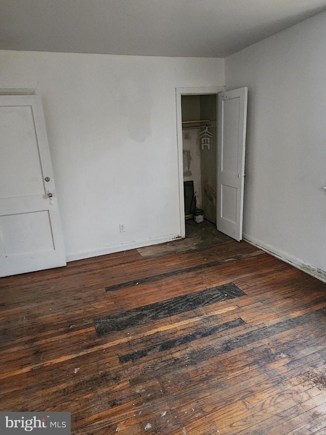 spare room featuring dark wood-type flooring and baseboards