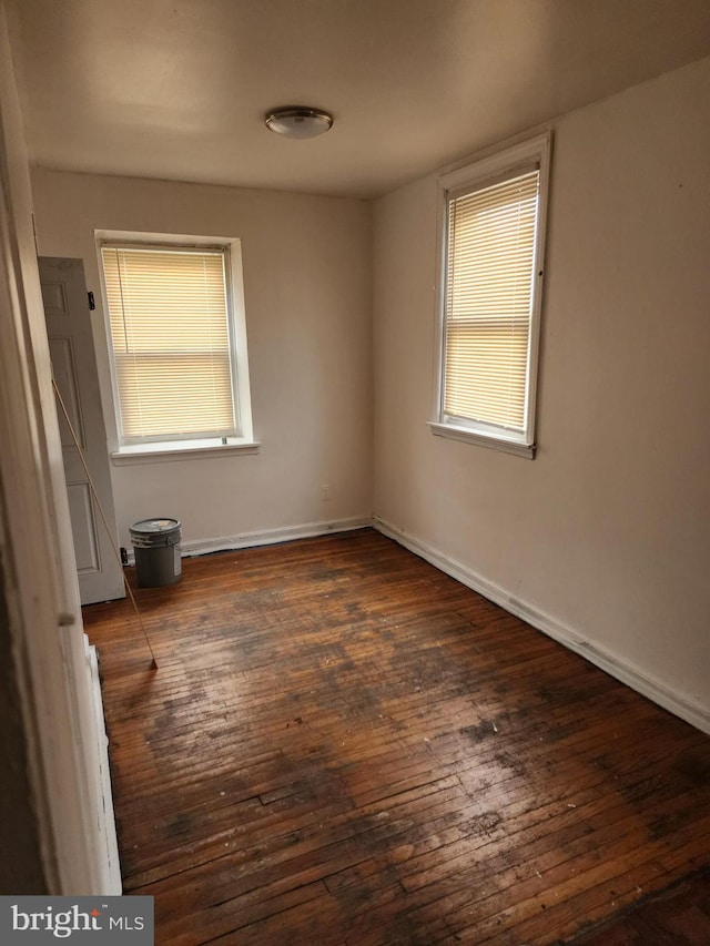 unfurnished bedroom with baseboards, multiple windows, and hardwood / wood-style floors