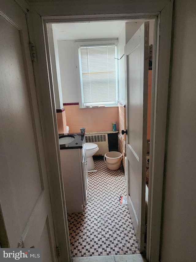 bathroom featuring wainscoting, vanity, toilet, tile patterned floors, and radiator