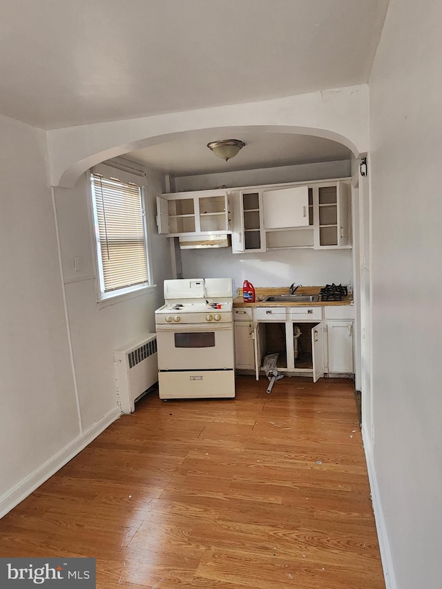 kitchen with open shelves, radiator, white gas stove, and arched walkways