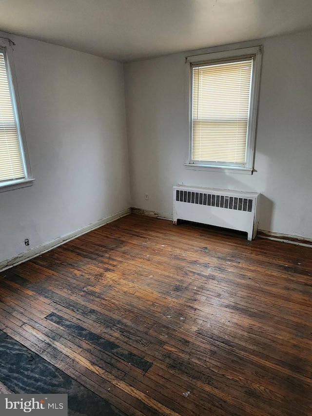 spare room featuring radiator heating unit and hardwood / wood-style floors