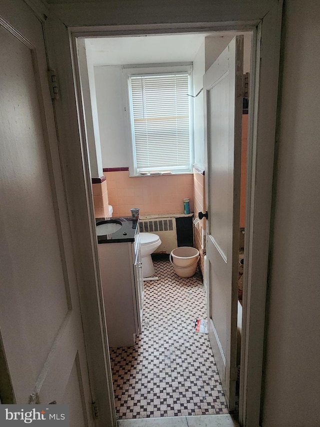 bathroom with wainscoting, tile patterned floors, vanity, toilet, and radiator heating unit