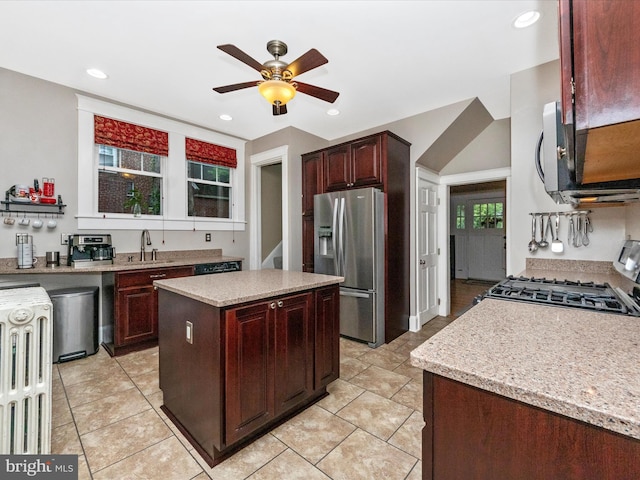 kitchen featuring light tile patterned flooring, ceiling fan, a sink, gas range, and stainless steel fridge