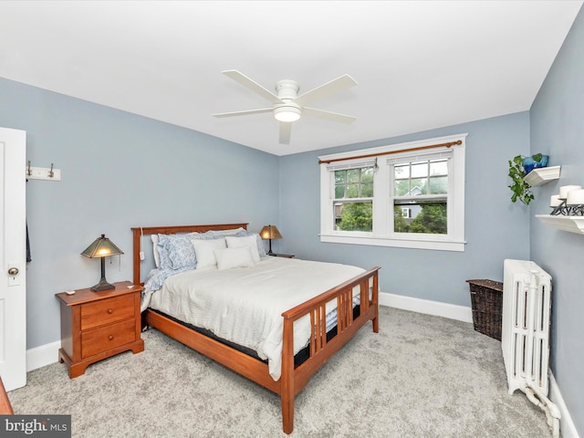 carpeted bedroom featuring baseboards, a ceiling fan, and radiator heating unit