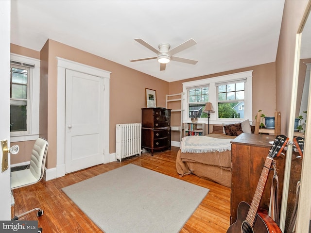bedroom with baseboards, radiator heating unit, ceiling fan, and wood finished floors