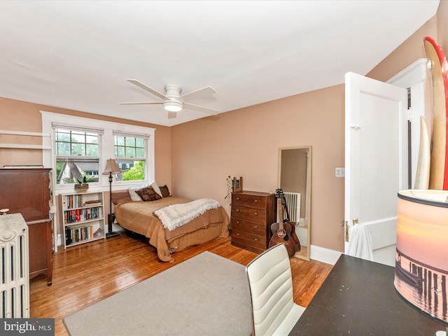 bedroom featuring wood finished floors, a ceiling fan, and radiator heating unit