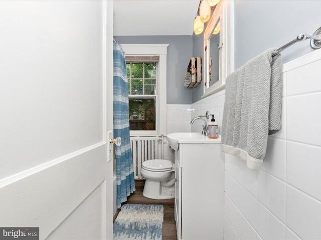 bathroom with tile walls, toilet, radiator heating unit, vanity, and wood finished floors