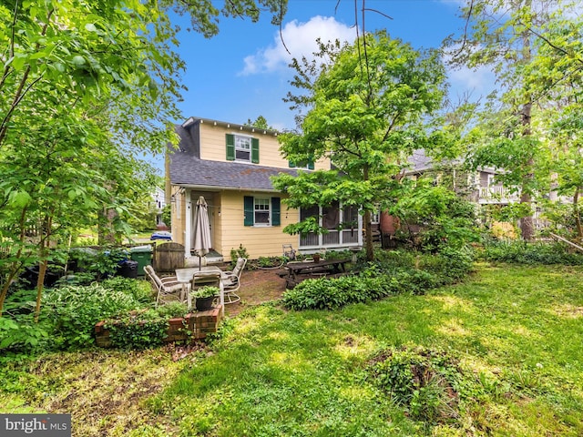 back of property with a yard, roof with shingles, and a sunroom