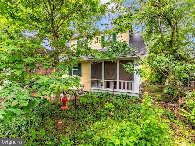 back of property with a sunroom and a shingled roof