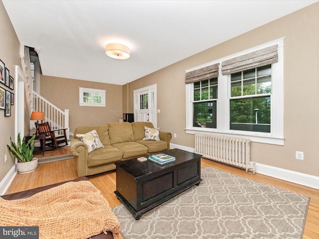 living room with light wood-style floors, baseboards, and radiator heating unit