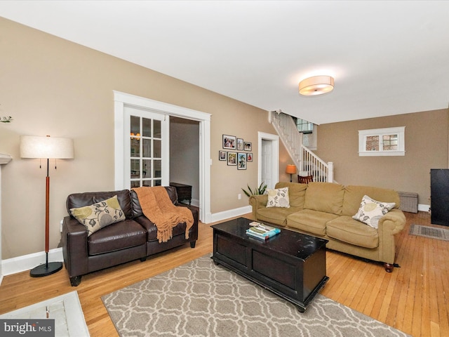 living area featuring stairs, baseboards, and wood finished floors