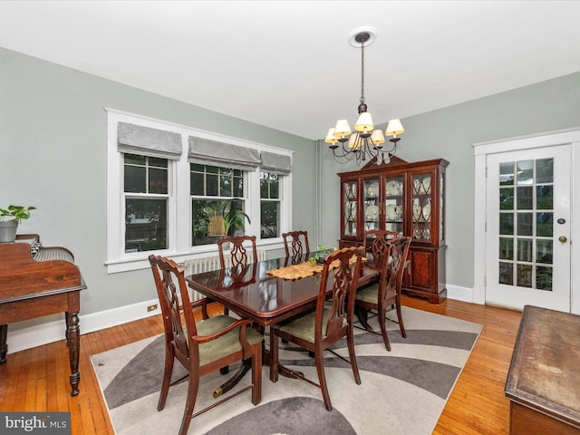 dining room featuring a notable chandelier, baseboards, and wood finished floors