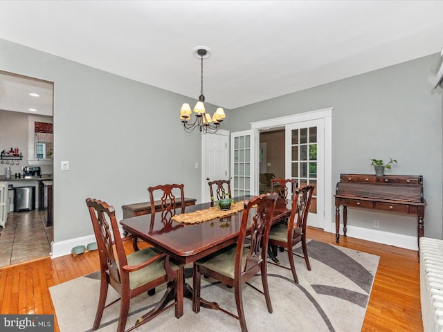 dining area with baseboards, light wood-style floors, radiator heating unit, and a chandelier