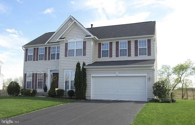 view of front of property featuring an attached garage, a front yard, and aphalt driveway