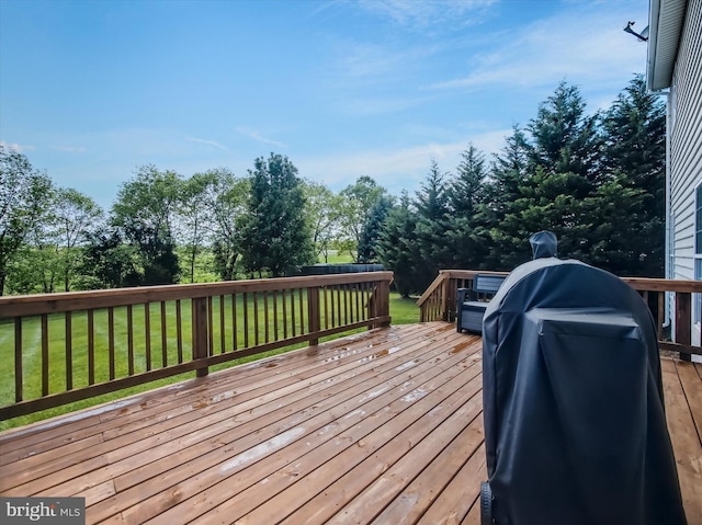 wooden terrace with a yard, grilling area, and view of scattered trees