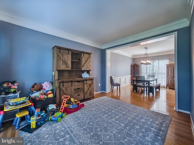 game room featuring a chandelier, ornamental molding, wood finished floors, and baseboards