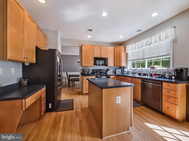 kitchen featuring black appliances, light wood finished floors, a kitchen island, dark countertops, and recessed lighting