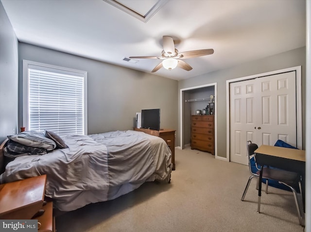bedroom featuring light carpet, multiple closets, and a ceiling fan