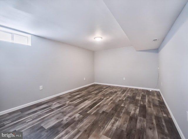 basement featuring dark wood-type flooring and baseboards
