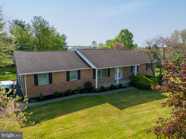 ranch-style house featuring a front yard, a porch, brick siding, and a shingled roof