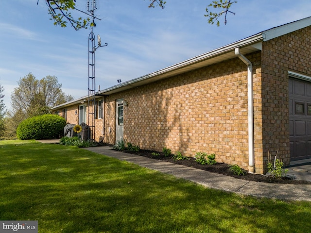 view of property exterior with an attached garage, brick siding, and a lawn