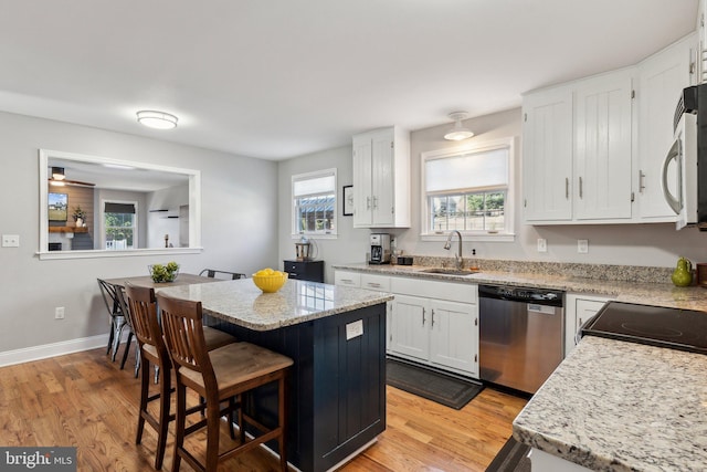 2994 Hope Mill Ln, Adamstown, MD 21710 - kitchen with light wood-style floors, stainless steel dishwasher, a breakfast bar area, and white cabinetry