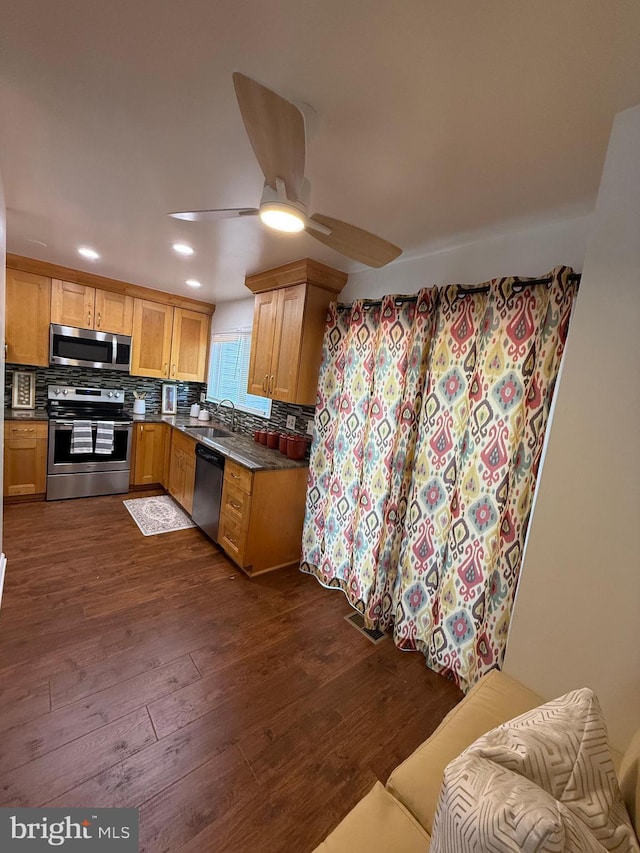 kitchen with dark countertops, dark wood finished floors, stainless steel appliances, and a sink
