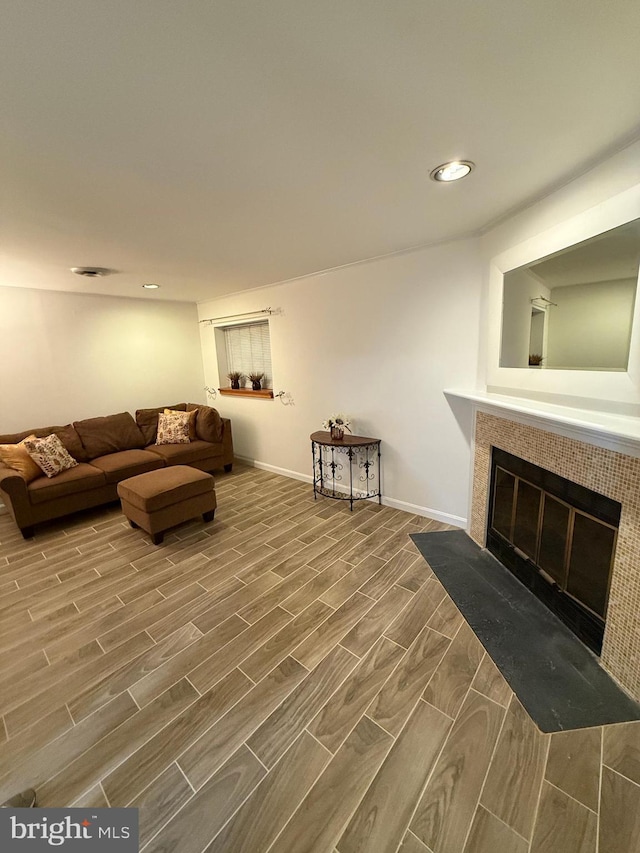living room featuring wood finish floors, baseboards, recessed lighting, and a tile fireplace