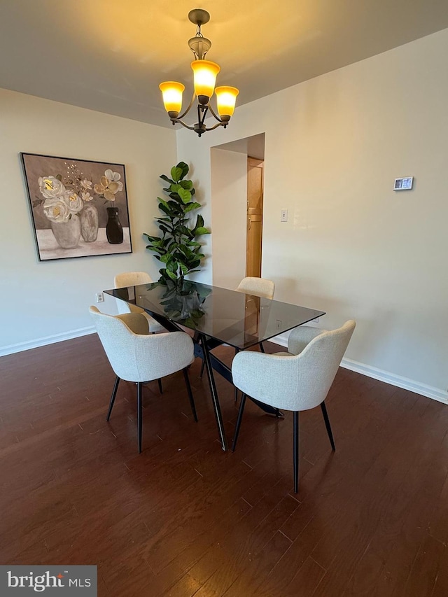 dining space featuring wood finished floors, baseboards, and a notable chandelier